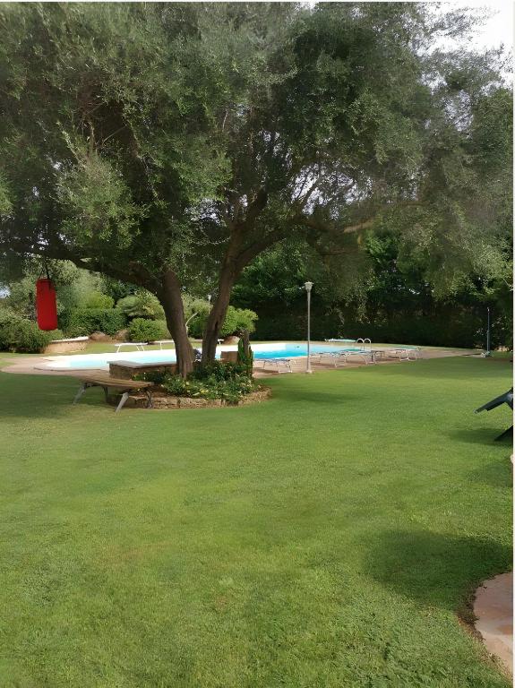 a park with a tree and a bench in the grass at Casa Pito Pito in Alghero