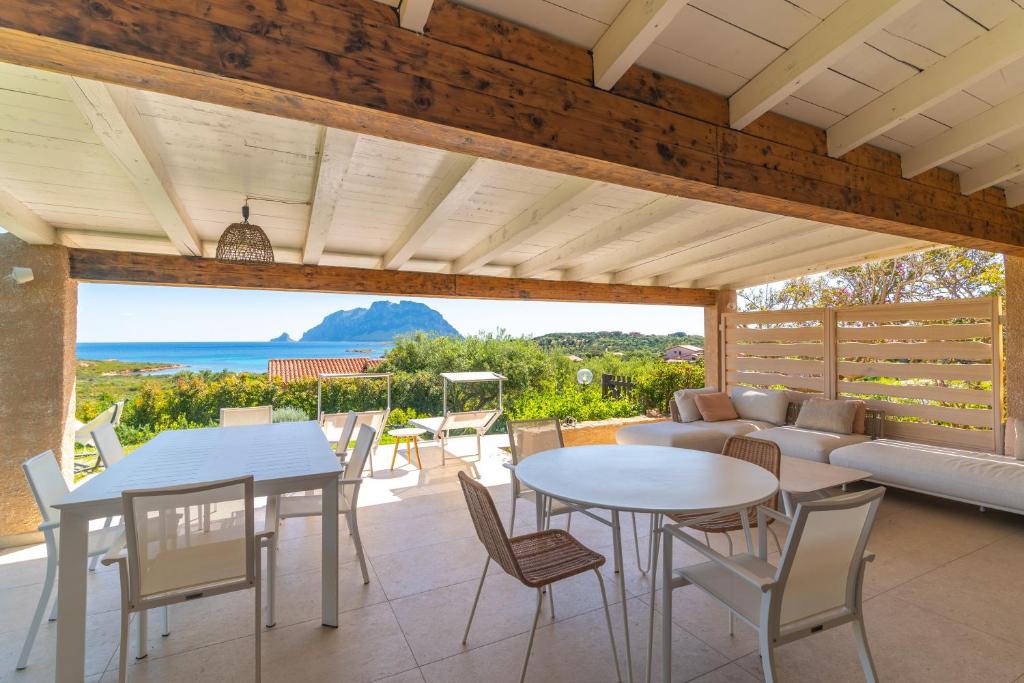 a patio with tables and chairs and a couch at Villa Cactus, Costa Corallina in Olbia