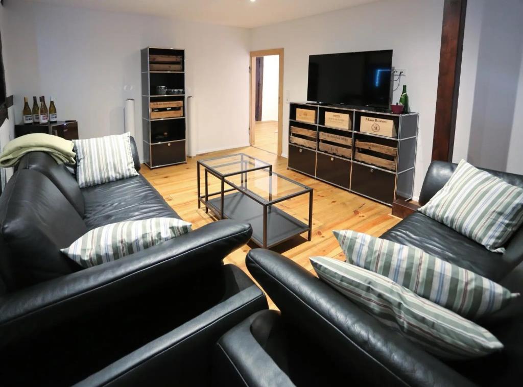 a living room with two leather couches and a television at Quartierblancdenoir Wohnungen in Reil