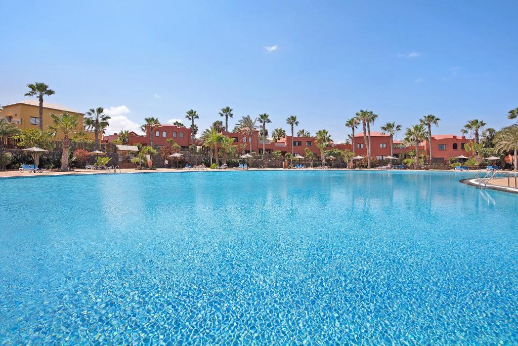 a large pool with blue water in a resort at La Casa De Los Sueños in Corralejo
