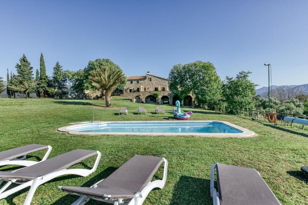 a yard with a pool with chairs and a house at Can Palau in Agullana