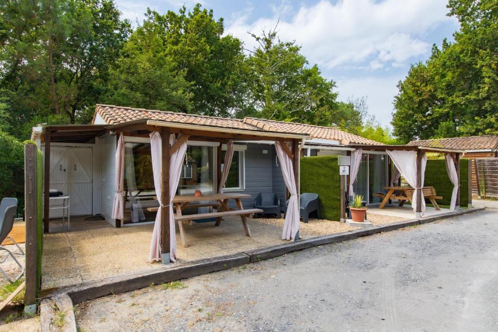 a wooden pavilion with a picnic table and a picnic table at Chalet A Village Vacances in Gujan-Mestras