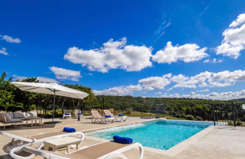 a swimming pool with chairs and an umbrella at Son Pons in Llucmajor