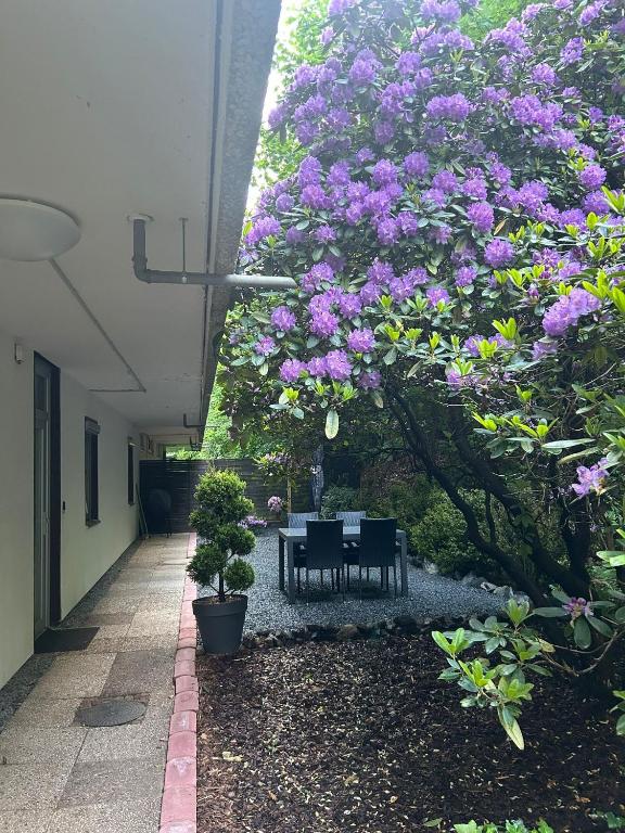 a table and chairs under a tree with purple flowers at Fewo Das Spatzennest in Bad Harzburg