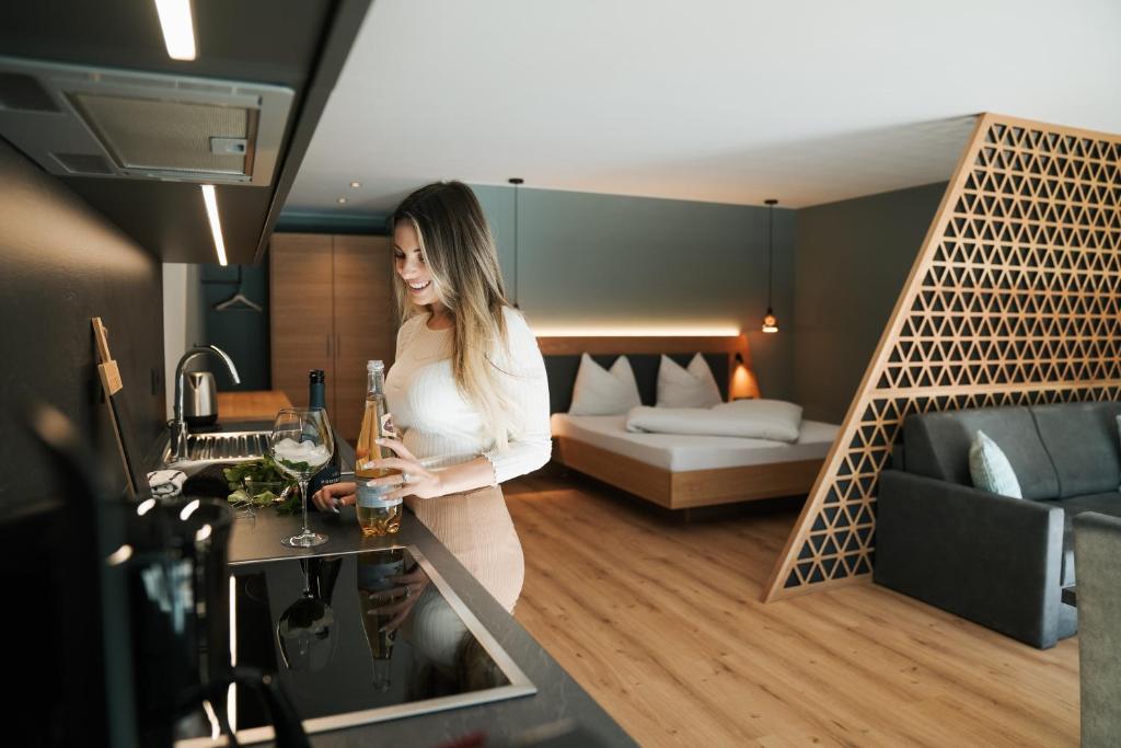 a woman standing at a bar in a hotel room at Aktiv Lodge Meran - Garden Two in San Martino