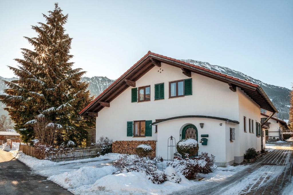 a house in the snow with a christmas tree at Ferienwohnung Carlina in Pfronten