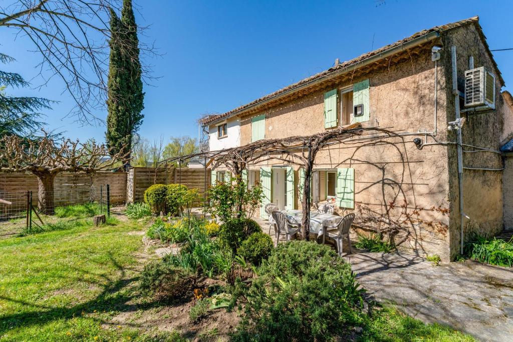 an old house with a table and chairs in the yard at La Tonnelle, clim, jardin in Malaucène
