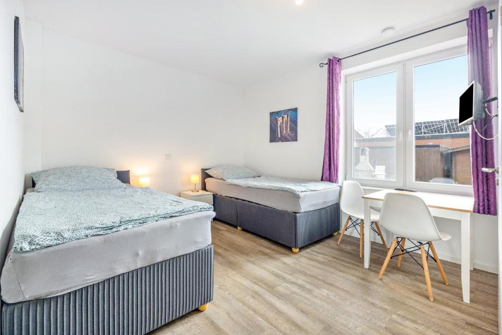 a bedroom with two beds and a desk and a window at Kleine Himmelpforte in Himmelpforten