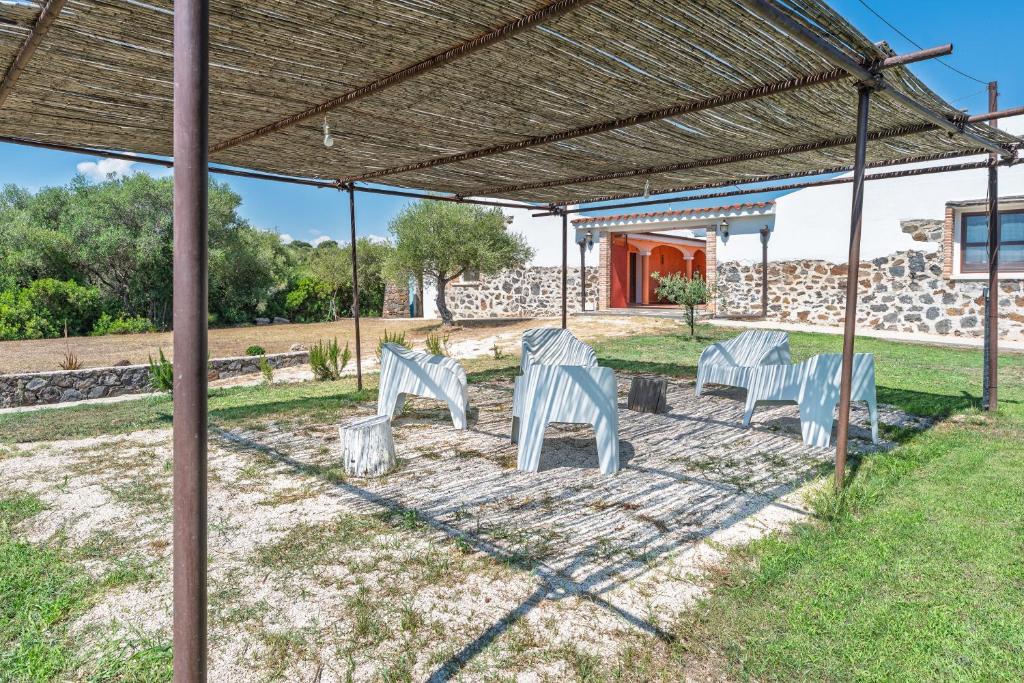 a group of white chairs sitting under a pergola at Villa Pedduzza in Orosei