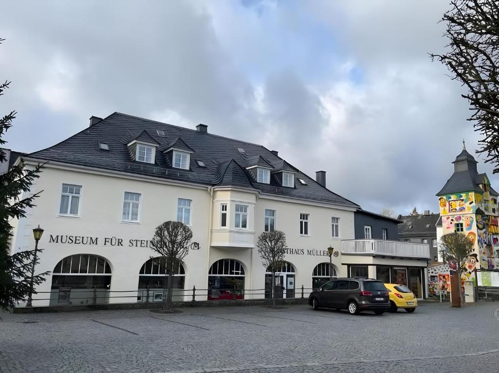 a large white building with cars parked in a parking lot at Ferienwohnung im ehem Rittergut in Wurzbach