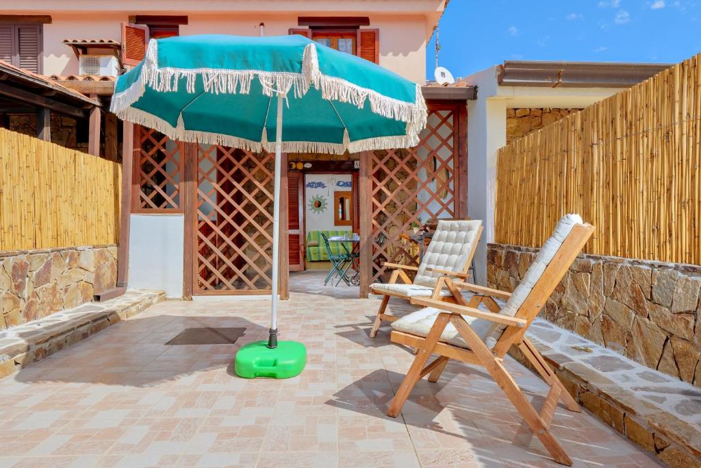 a patio with a green umbrella and two chairs at Casa Asfodeli in San Teodoro