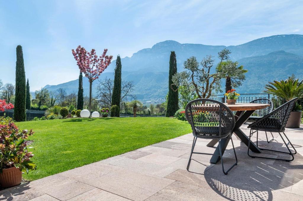 a patio with a table and chairs and a lawn at Haus Rosengarten Apt C in Terlano