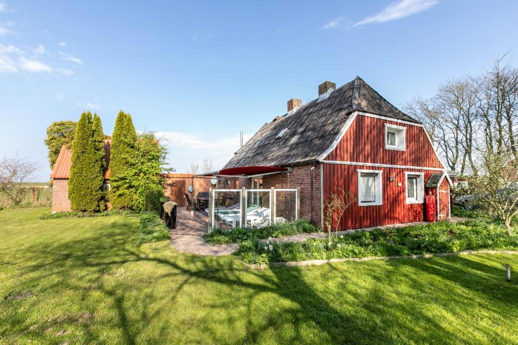 an old red barn with a grassy yard at Ferienhaus Busch in Elpersbüttel