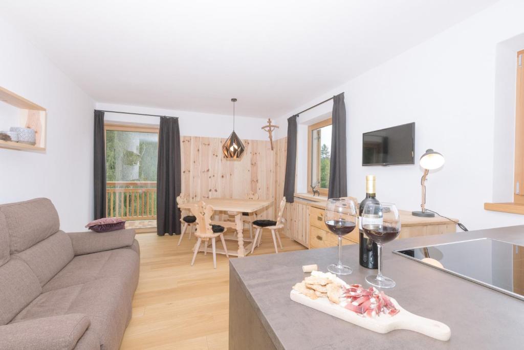 a living room with a couch and a table with wine glasses at Ferienwohnung Berg Wieserhof in Aldino