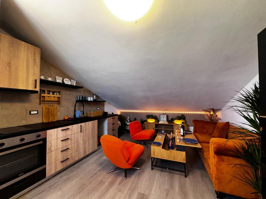 a living room with orange chairs and a kitchen at Nice and cozy apprtment in Murazzano with panoramic view in Murazzano