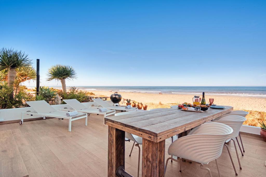 a wooden table and chairs on the beach at Denia Beach Lodge in Denia