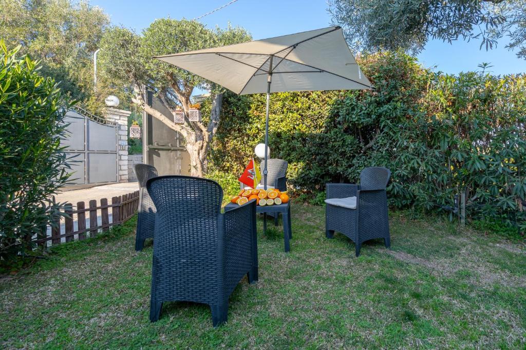 a table and chairs with an umbrella in the yard at Ciumara East in Avola