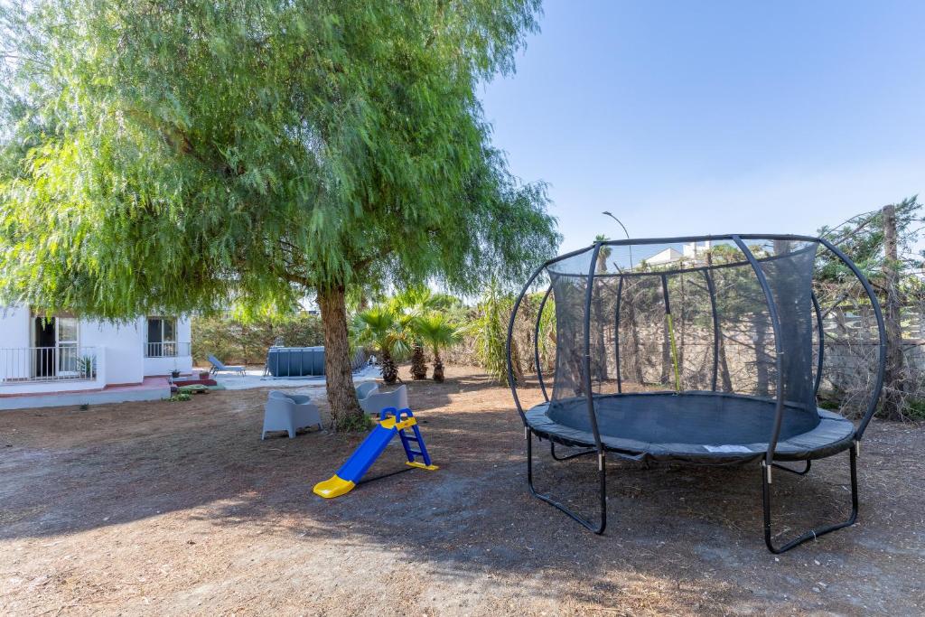 a swing set in a yard next to a tree at Villa Tosca dell'Angelo con piscina in Comiso
