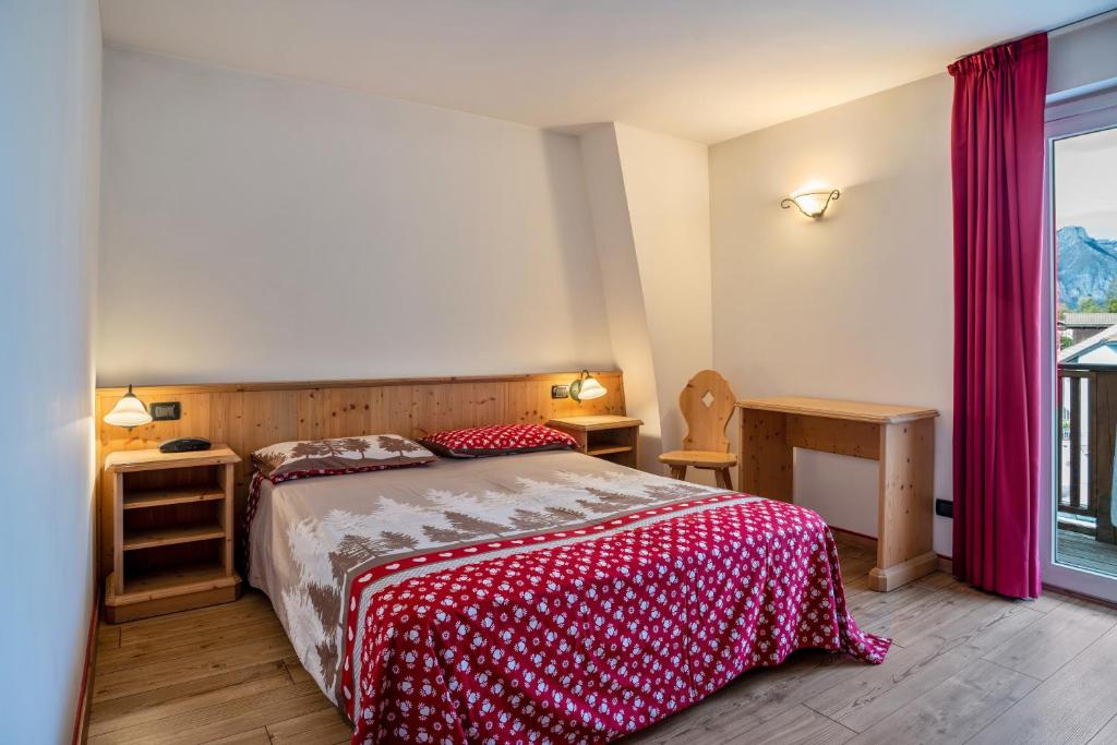 a bedroom with a bed with a red and white bedspread at Giongo Residence Aparthotel 101 in Lavarone