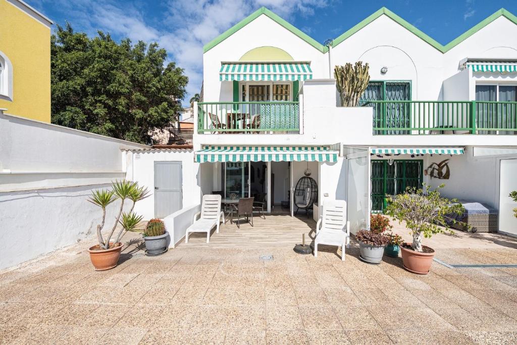 a large white house with chairs and plants at Pomelo vacacional in Arguineguín