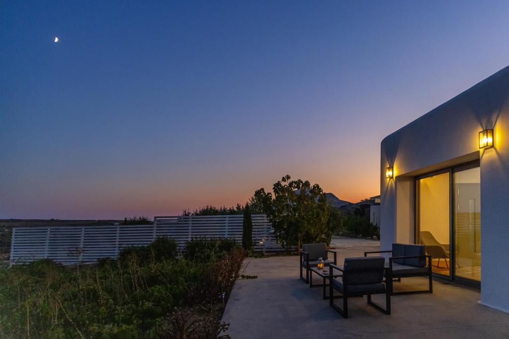 a patio with chairs and a table at dusk at A The Country House in Tinos
