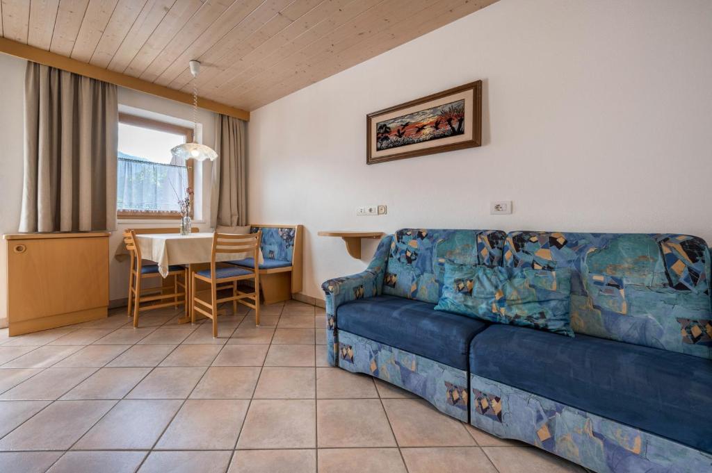 a living room with a blue couch and a table at App Sonne Nr 21 in Lutago