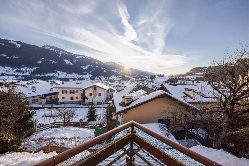 a view of a snow covered village with the sun setting at Appartamento Cornon in Tesero