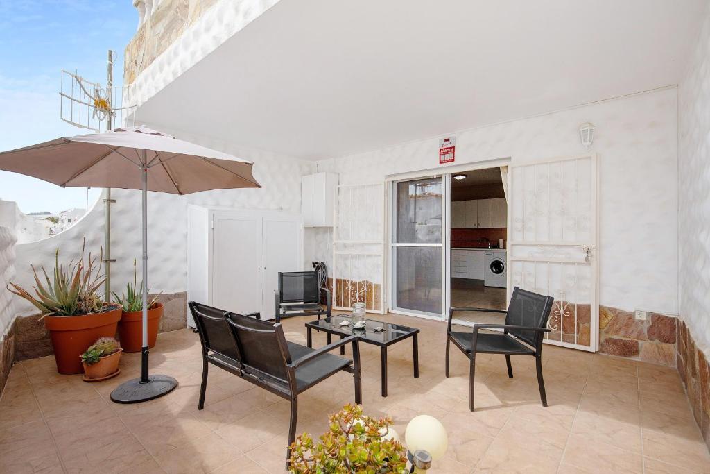 a patio with a table and chairs and an umbrella at Casa Weimar in Costa Calma