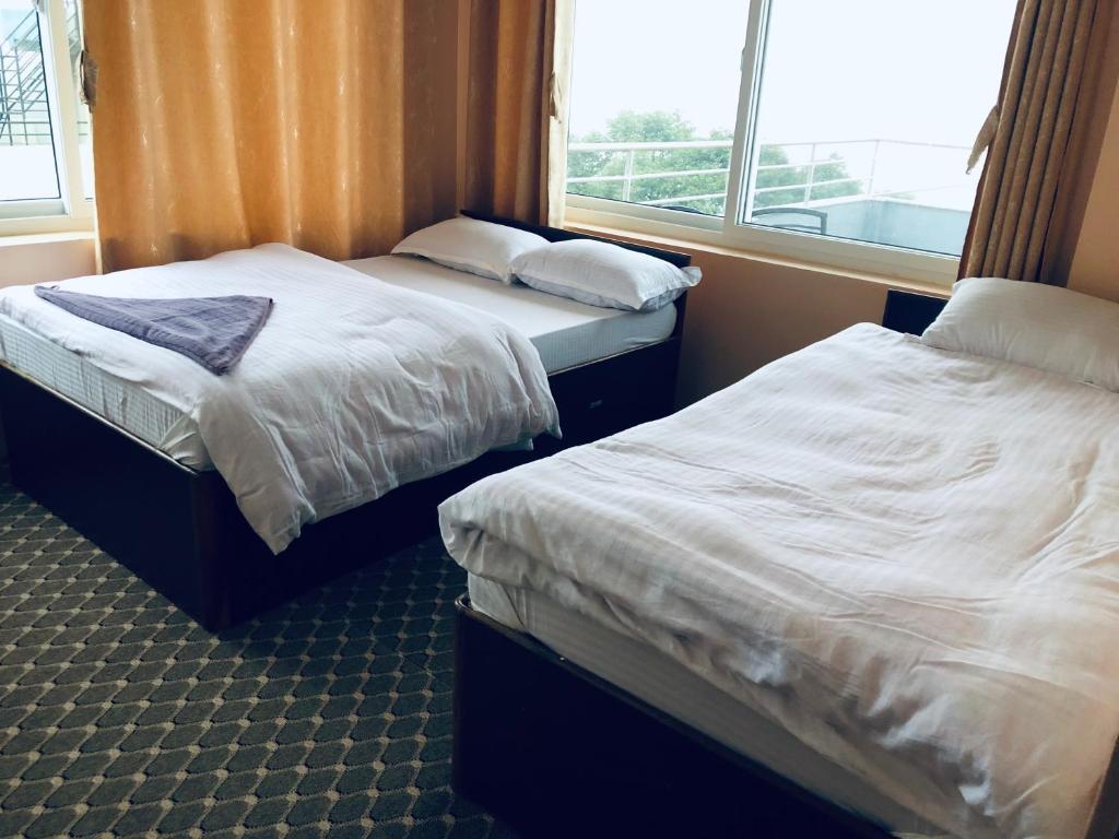 two beds in a room with a window at Manakamana hotel in Pāti Bhanjyāng