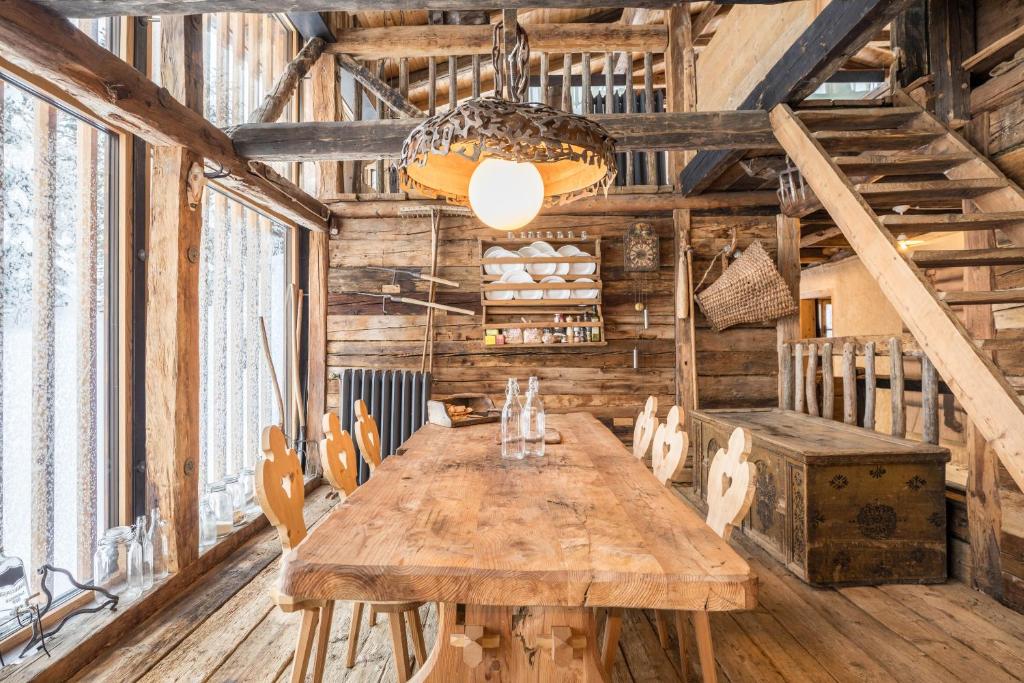 a dining room with a wooden table and chairs at Tannhäuser Mountain Chalet in Predoi