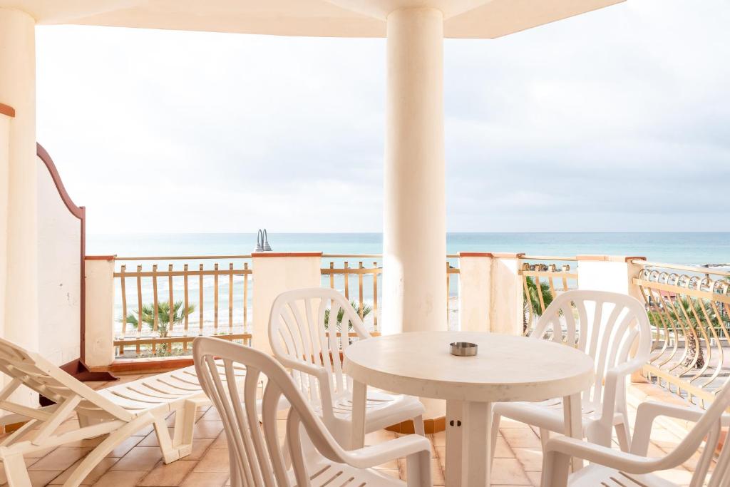a white table and chairs on a balcony with the ocean at Appartamento D - Le Terrazze in Ribera