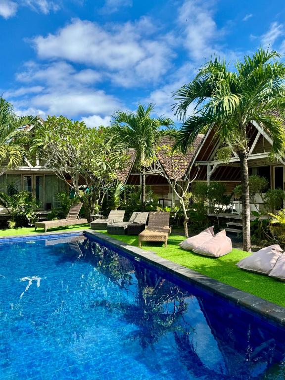 a swimming pool with palm trees and a house at Danys House at Tiki Bar and More in Nusa Lembongan