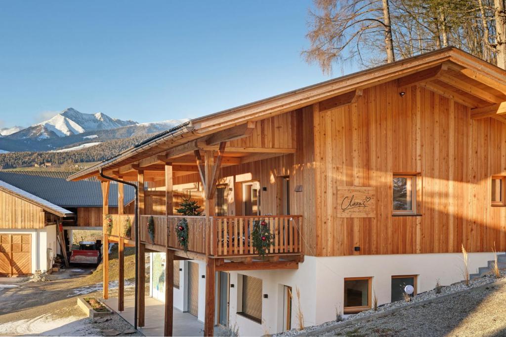 a house with a wrap around deck with mountains in the background at Lechnerhof - Clara´s Mountain Lodge in Rodengo