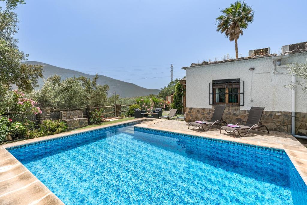 a swimming pool in front of a house at Las Gallinas Cottage Orgiva in Órgiva