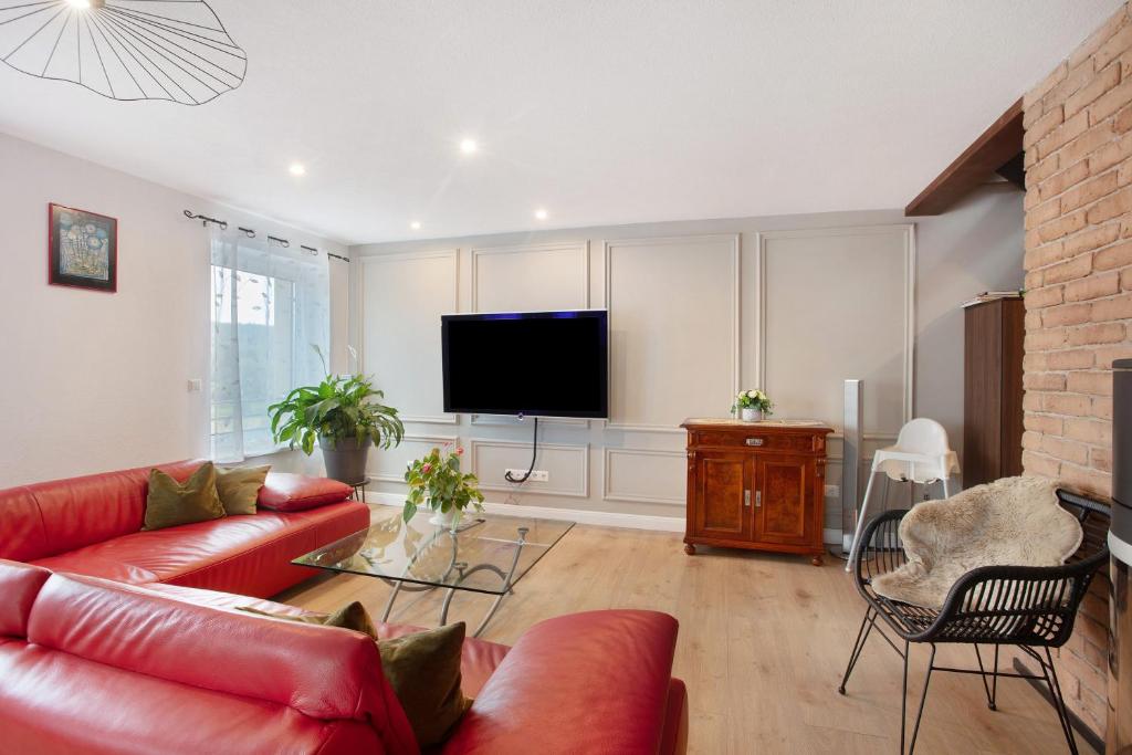 a living room with a red couch and a flat screen tv at Heimelige Schwarzwaldwohnug Berg in Häusern