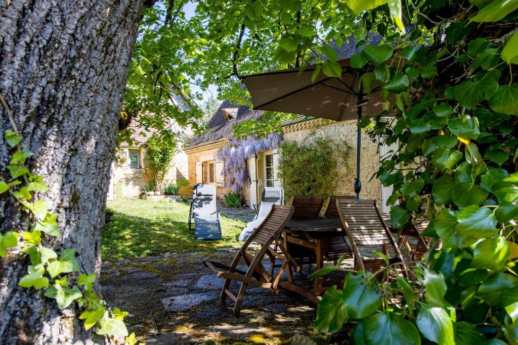 a table and chairs under an umbrella in a yard at Les Gabernous in Tursac
