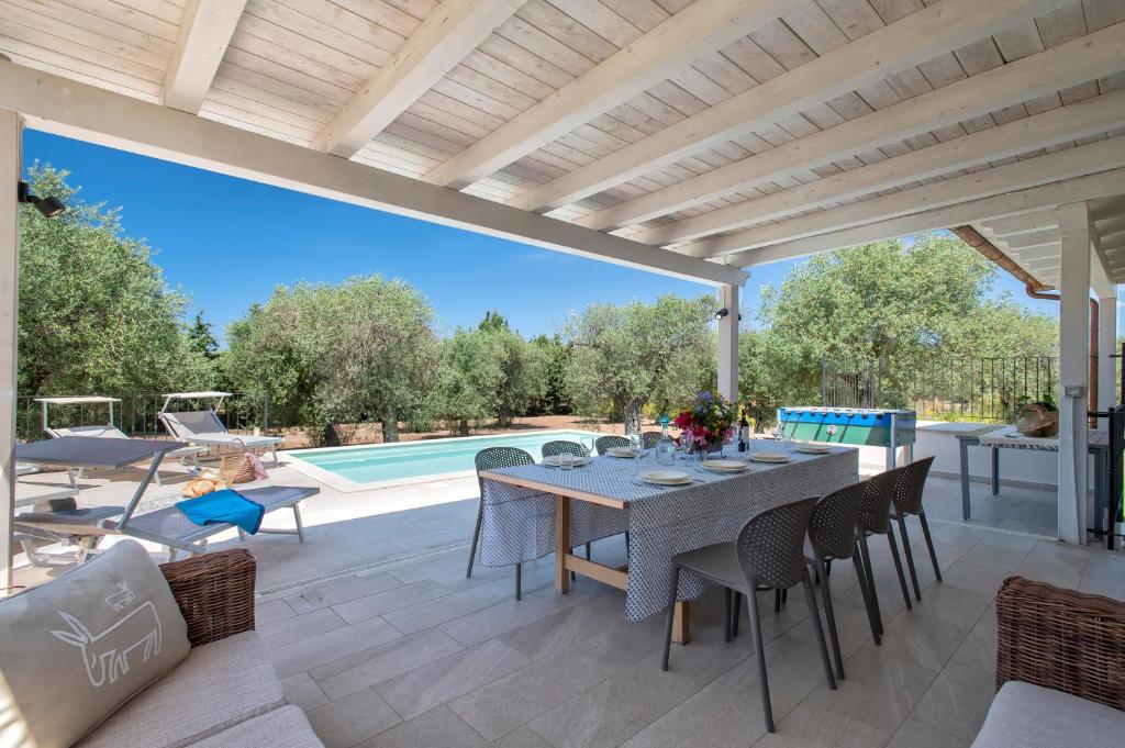 a patio with a table and chairs and a pool at Villa Olivetta con piscina in Alghero