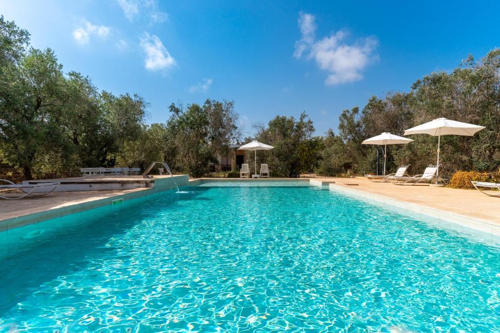 a swimming pool with blue water and umbrellas at Domus mea salento Arazzo Blu in Ugento