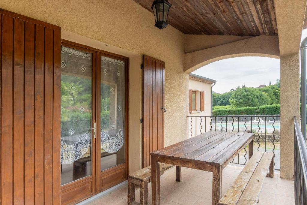 a porch with a wooden table and a balcony at Les Sources Gite Cabernet in Chambonas