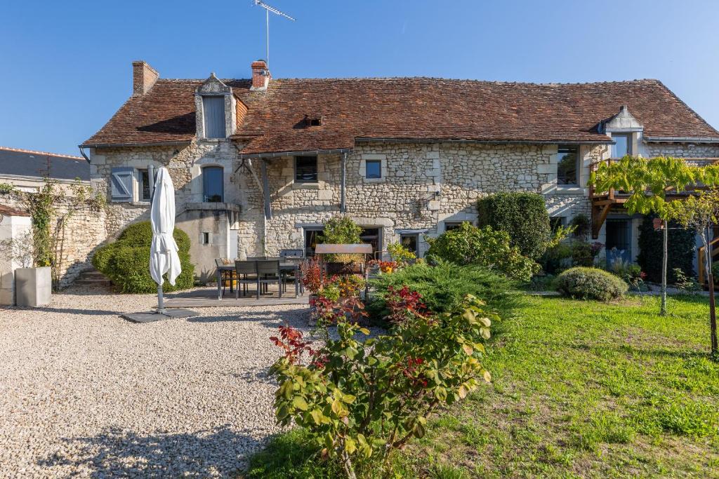 a large stone house with a table and an umbrella at Au Bo Voyage in Tavant