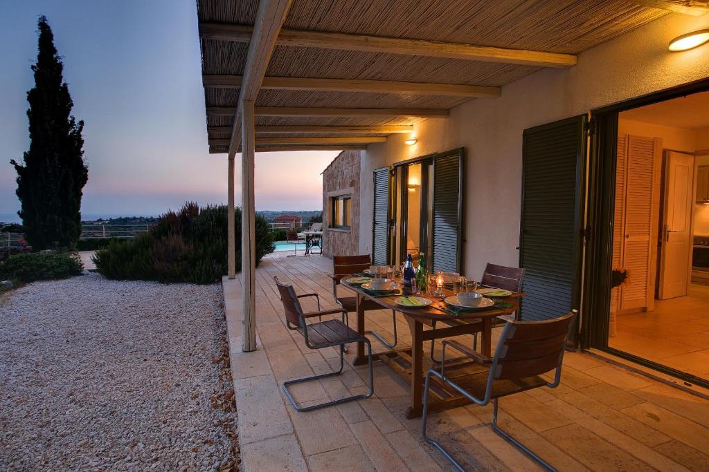 a patio with a table and chairs on a balcony at Villa Mataki Ideales Resort in Kefallonia