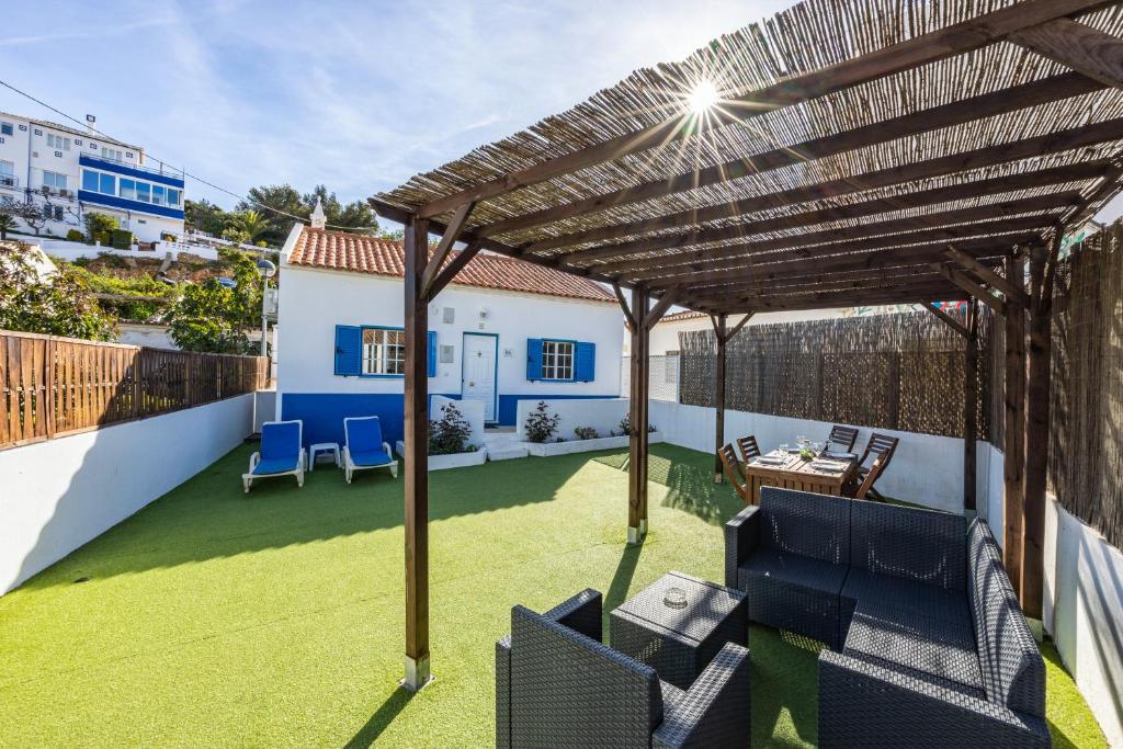 a patio with chairs and a wooden pergola at Salema Beach House in Salema
