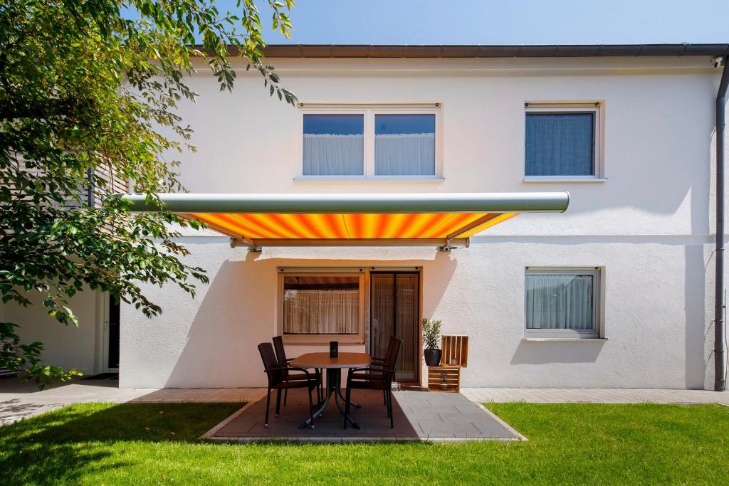 a patio with a table and chairs in front of a house at Ferienwohnung am Alenberg in Münsingen
