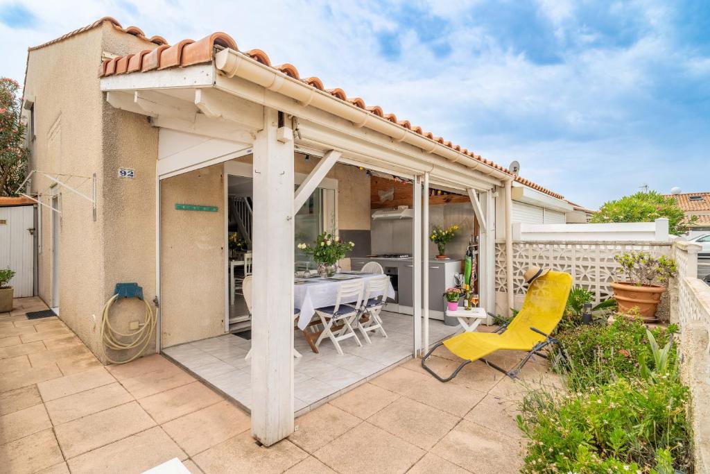a patio with a table and a yellow chair at Maison 38m2 proche de la mer in Gruissan