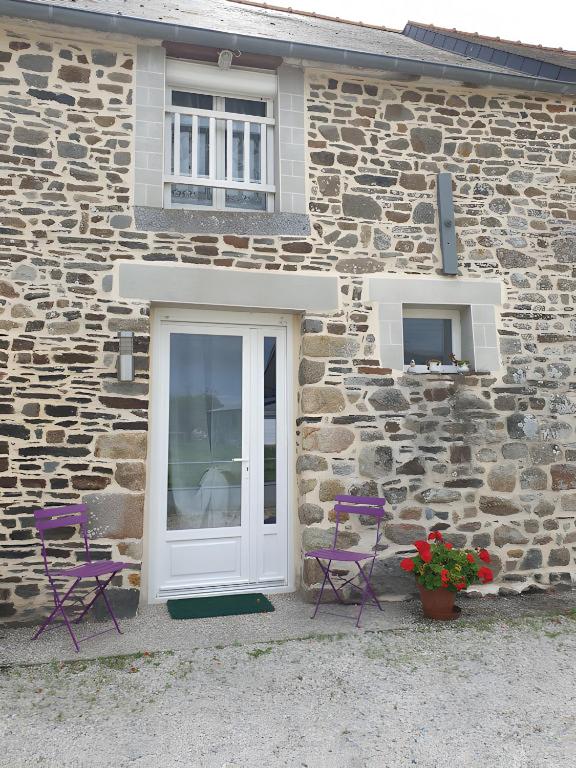a stone house with two purple chairs and a white door at Chambre Chanteloup in Mont-Dol