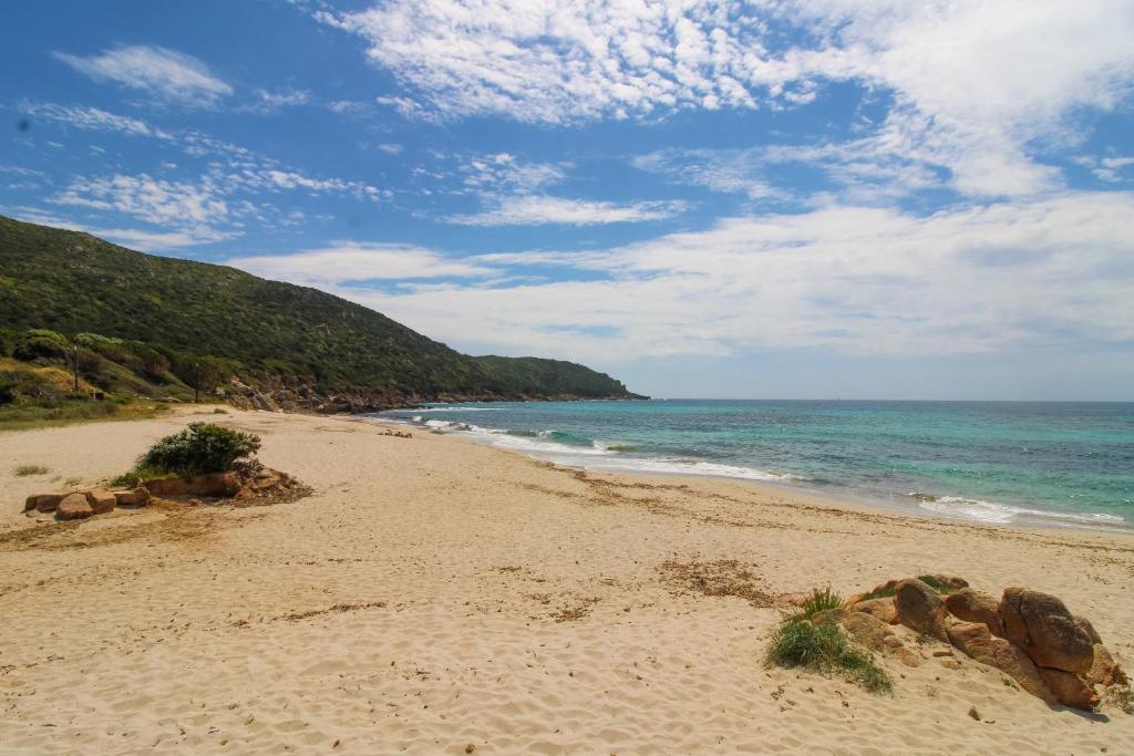 a beach with rocks and the ocean on a cloudy day at Le Chalet De La Plage in Coti-Chiavari
