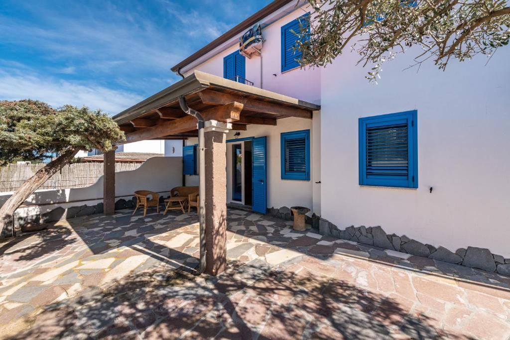 a patio with a wooden pergola in front of a house at Sottotorre 1 in Calasetta