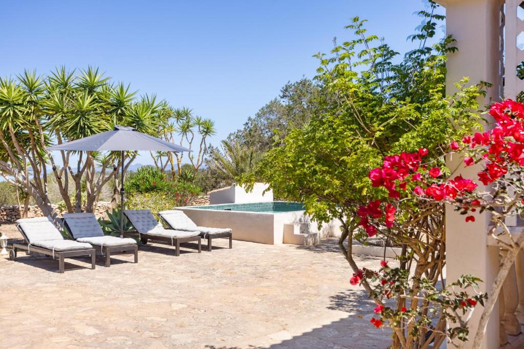 a patio with chairs and a pool with red flowers at Casa Can Mussenya in Illes Balears