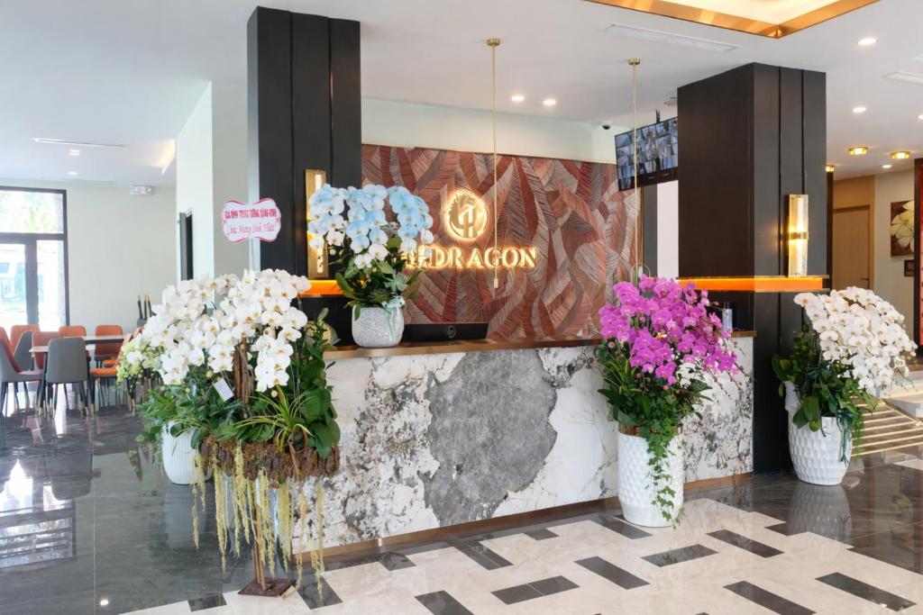 a lobby with flowers in vases on a wall at H- Dragon Hotel in Ðố Sơn