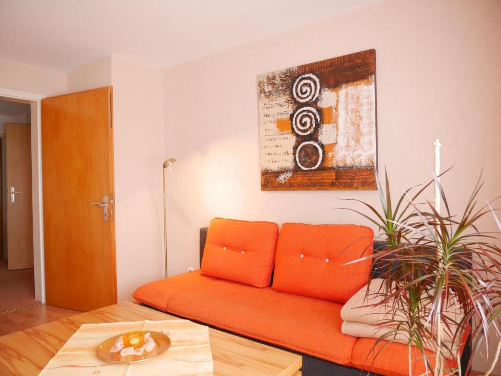 an orange couch in a living room with a table at Börsighof in Seebach